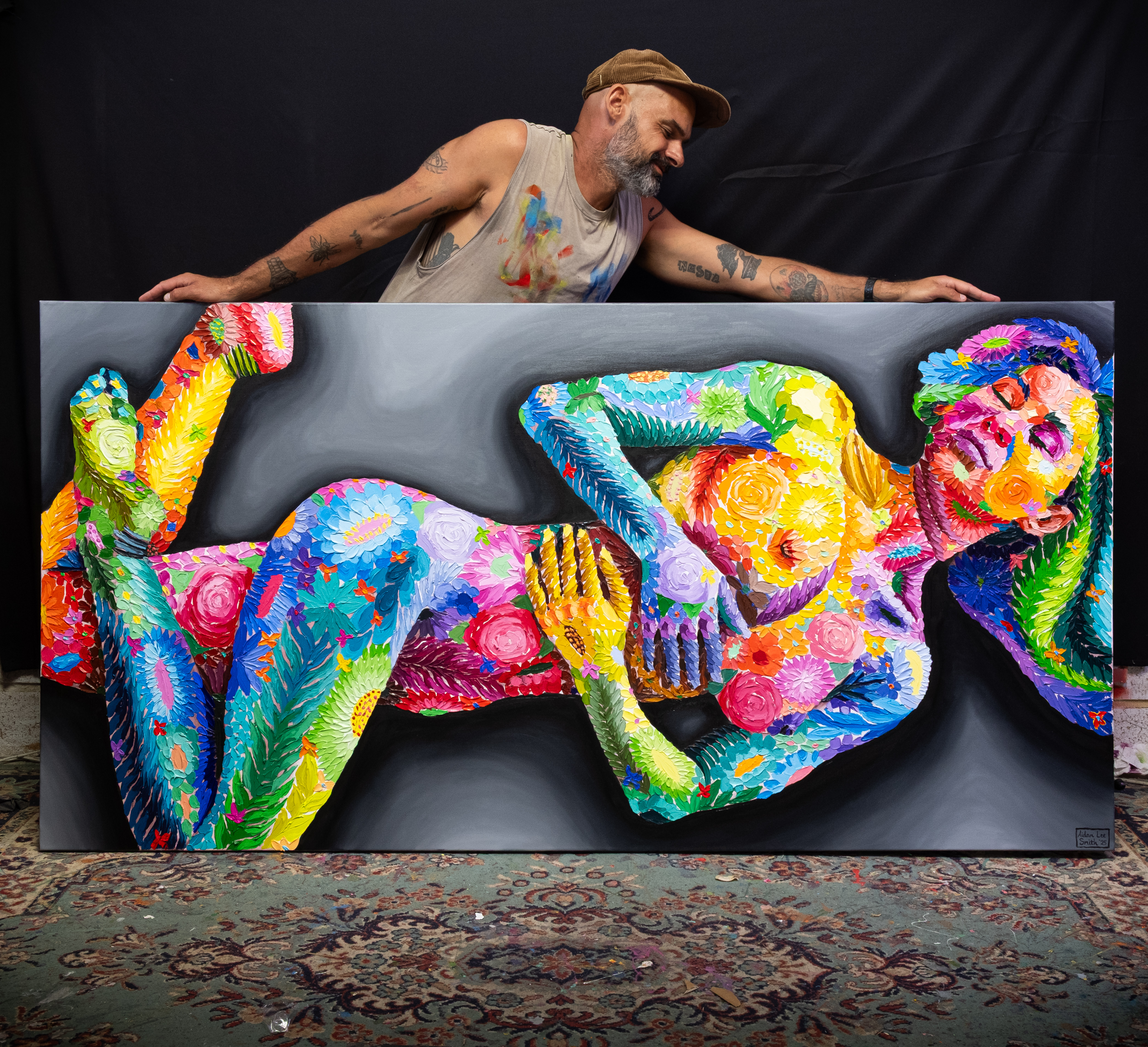 man holding up a large painting of a vibrantly coloured nude woman